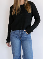 Woman wearing the Z Supply Medina Pointelle Cardigan, a black cable pointelle knit button-front cardigan