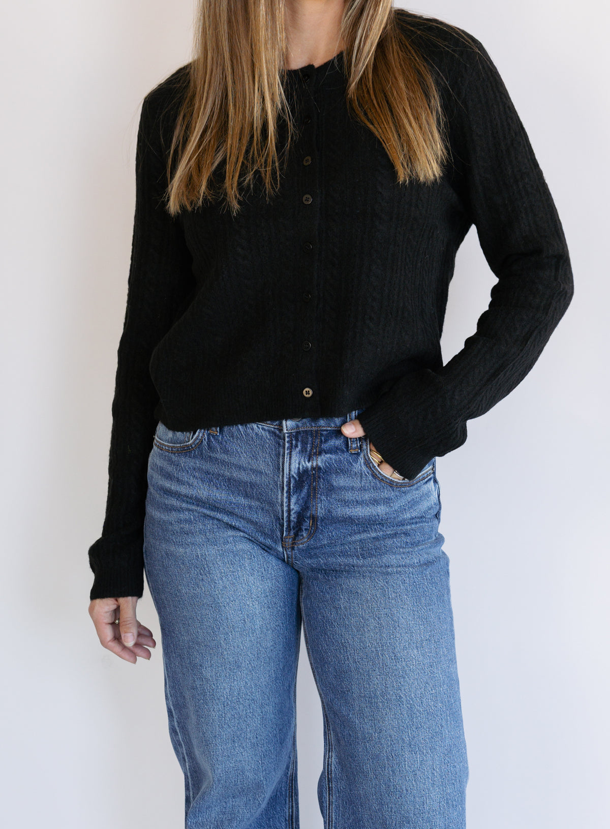 Woman wearing the Z Supply Medina Pointelle Cardigan, a black cable pointelle knit button-front cardigan
