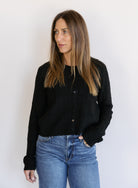 Woman wearing the Z Supply Medina Pointelle Cardigan, a black cable pointelle knit button-front cardigan