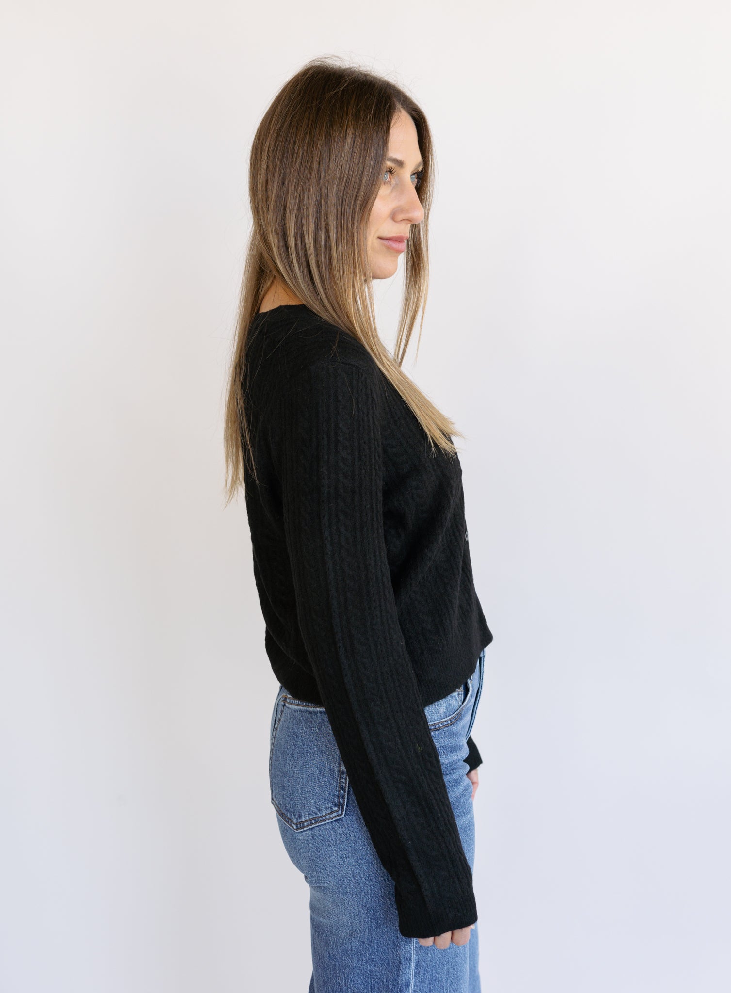 Woman wearing the Z Supply Medina Pointelle Cardigan, a black cable pointelle knit button-front cardigan