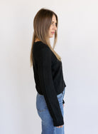 Woman wearing the Z Supply Medina Pointelle Cardigan, a black cable pointelle knit button-front cardigan
