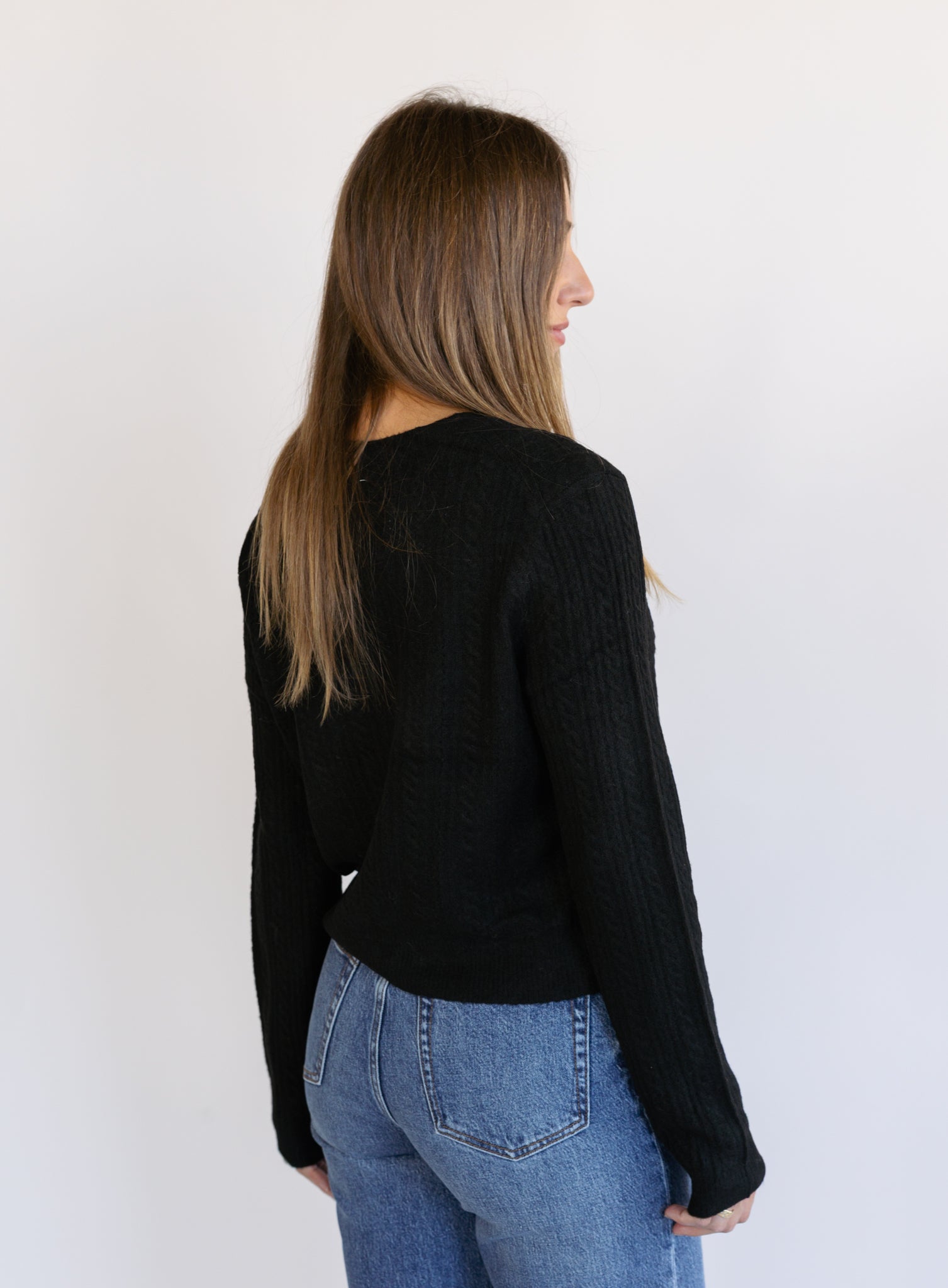 Woman wearing the Z Supply Medina Pointelle Cardigan, a black cable pointelle knit button-front cardigan