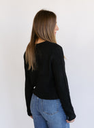 Woman wearing the Z Supply Medina Pointelle Cardigan, a black cable pointelle knit button-front cardigan