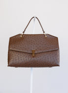 Beatrice Satchel, a brown ostrich-embossed top-handle bag with a gold bar clasp
