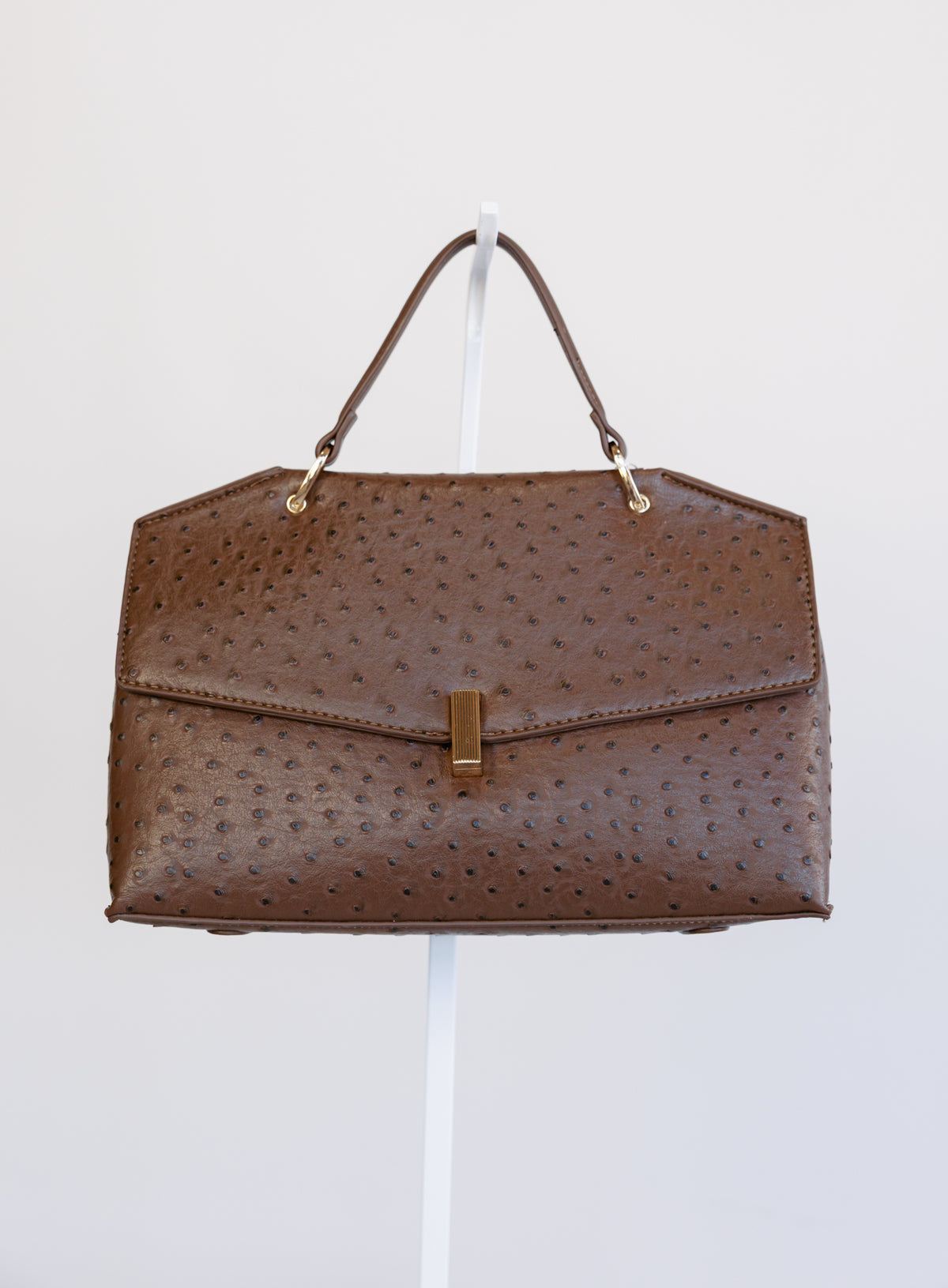 Beatrice Satchel, a brown ostrich-embossed top-handle bag with a gold bar clasp