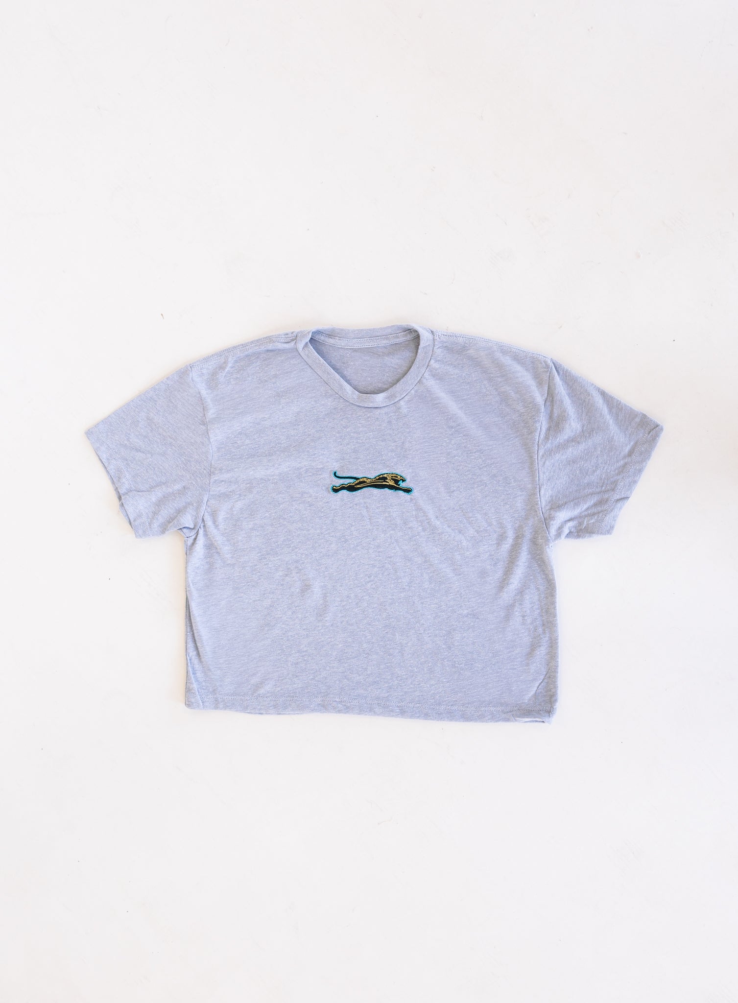 Jags Embroidered Crop Tee, a heather grey crewneck crop tee with a teal and gold embroidered jaguar
