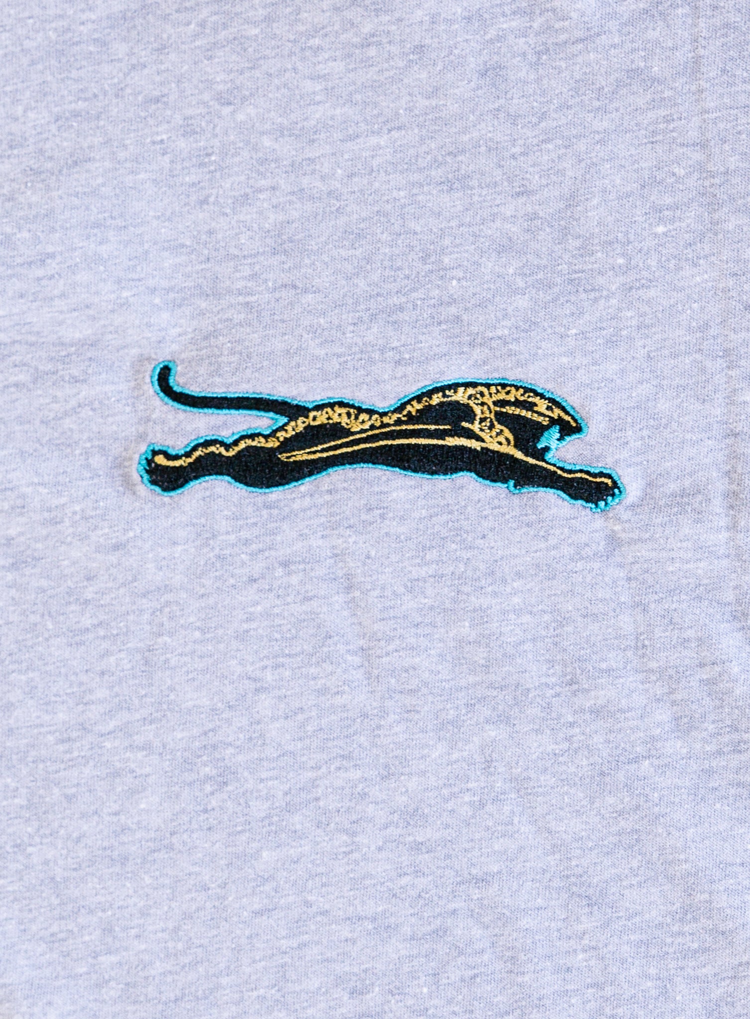 Jags Embroidered Crop Tee, a heather grey crewneck crop tee with a teal and gold embroidered jaguar