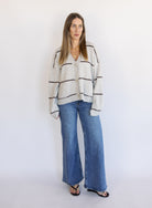 Woman wearing the Juno Striped Knit Cardigan, a mushroom knit cardigan with chocolate stripes and a V-neck