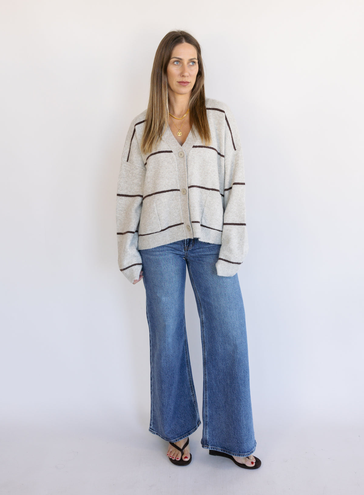 Woman wearing the Juno Striped Knit Cardigan, a mushroom knit cardigan with chocolate stripes and a V-neck