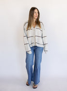 Woman wearing the Juno Striped Knit Cardigan, a mushroom knit cardigan with chocolate stripes and a V-neck
