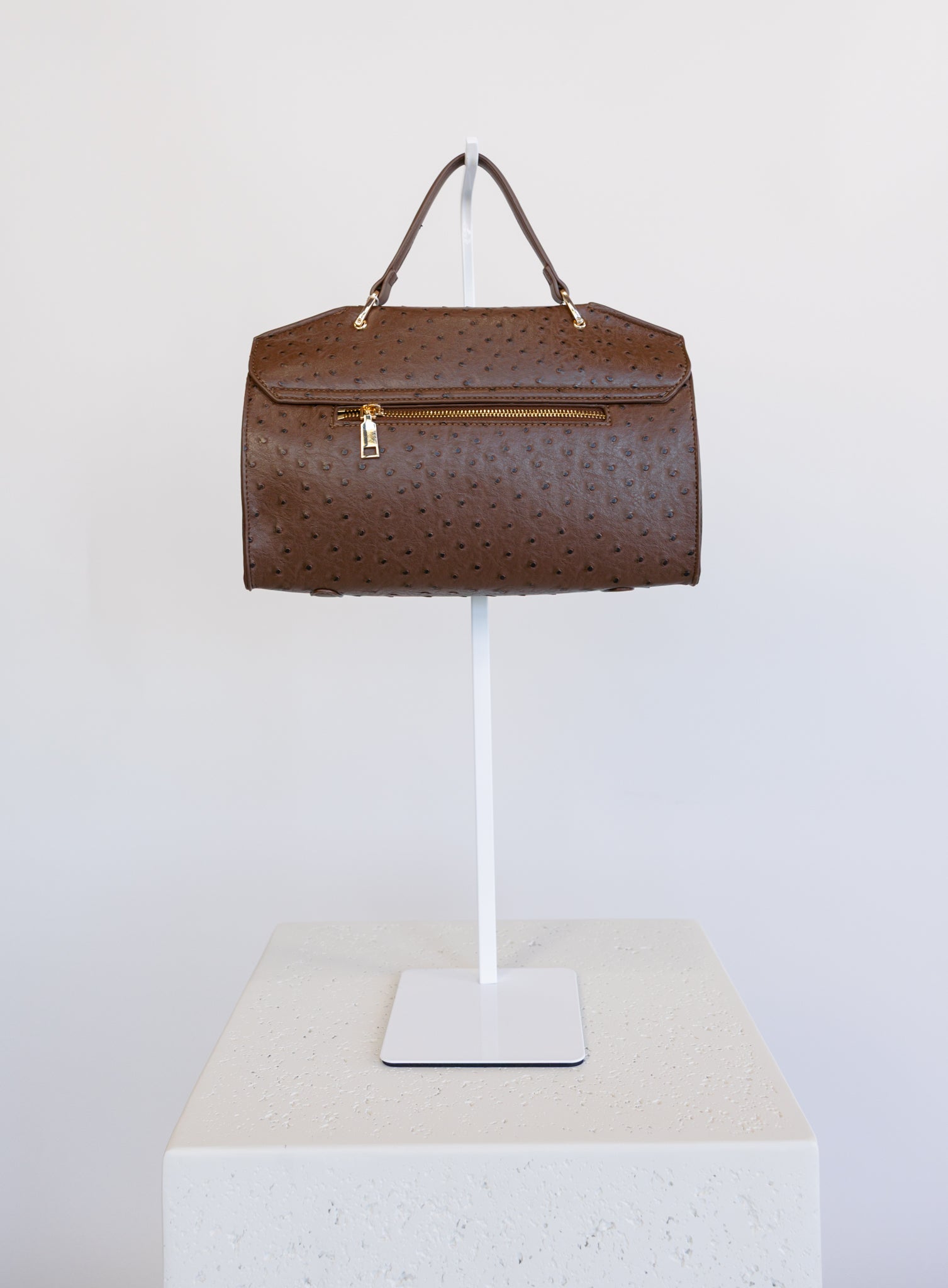 Beatrice Satchel, a brown ostrich-embossed top-handle bag with a gold bar clasp