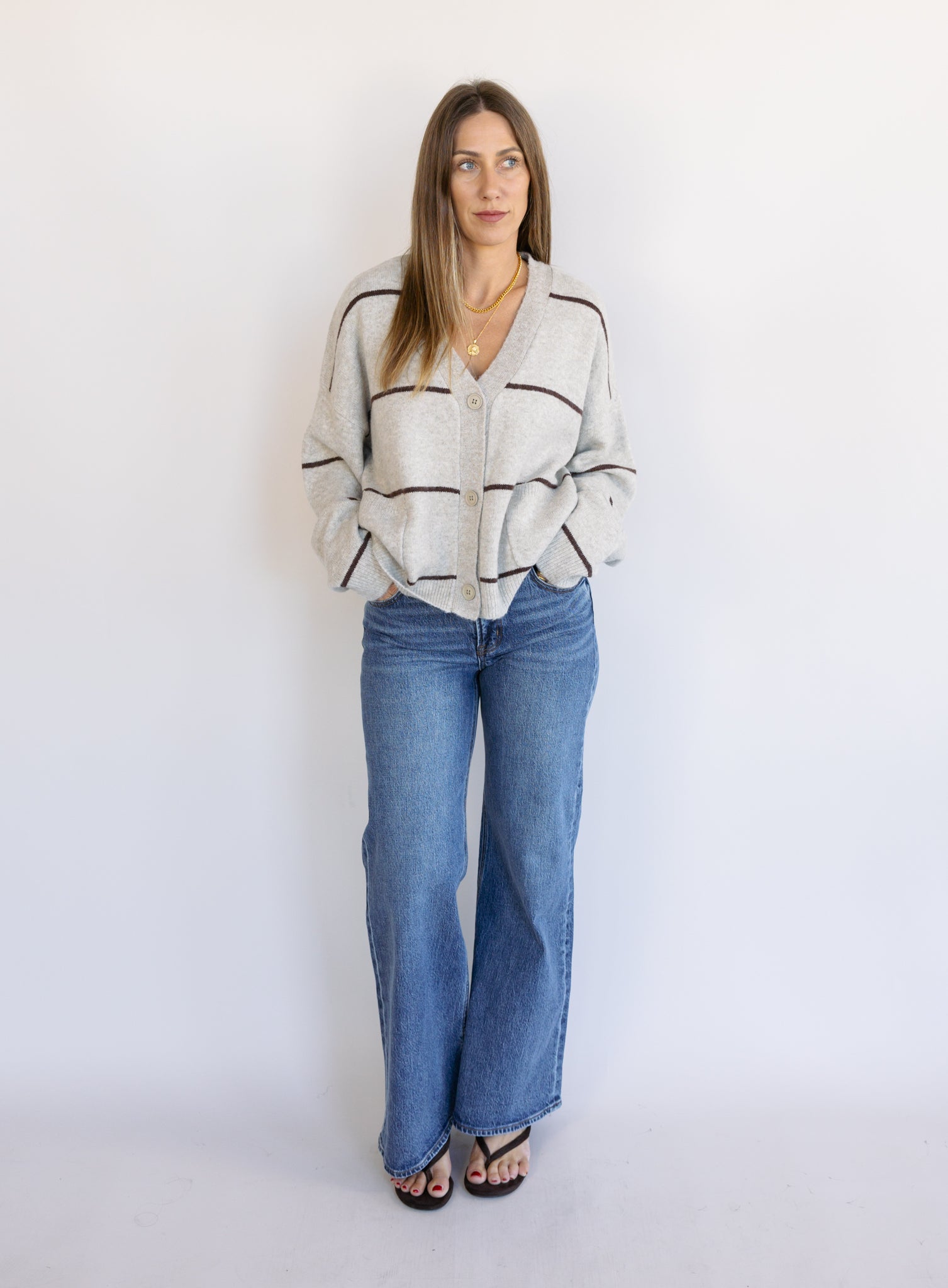 Woman wearing the Juno Striped Knit Cardigan, a mushroom knit cardigan with chocolate stripes and a V-neck