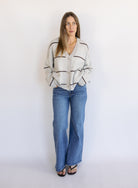Woman wearing the Juno Striped Knit Cardigan, a mushroom knit cardigan with chocolate stripes and a V-neck