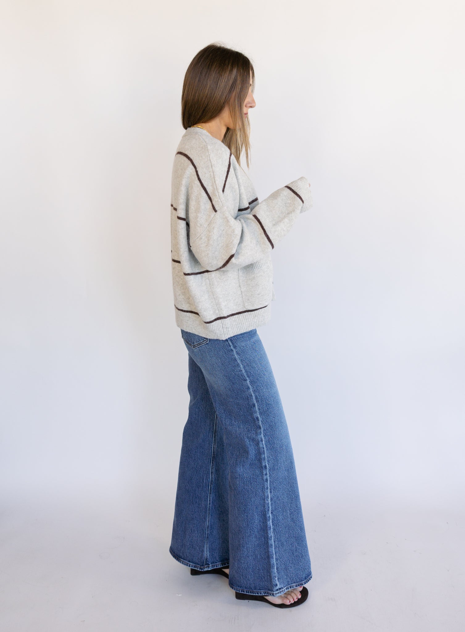 Woman wearing the Juno Striped Knit Cardigan, a mushroom knit cardigan with chocolate stripes and a V-neck