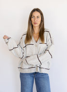 Woman wearing the Juno Striped Knit Cardigan, a mushroom knit cardigan with chocolate stripes and a V-neck