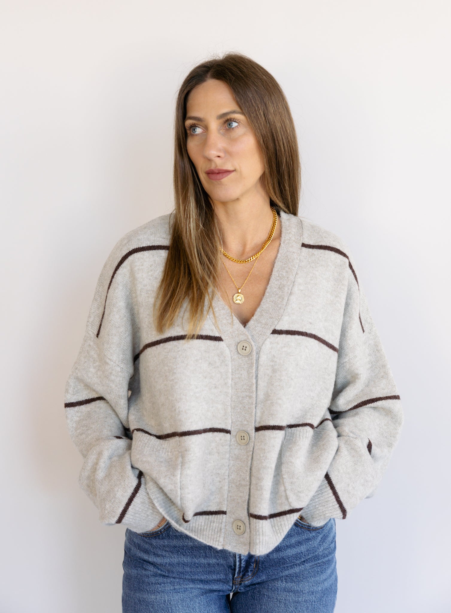 Woman wearing the Juno Striped Knit Cardigan, a mushroom knit cardigan with chocolate stripes and a V-neck