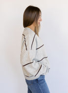 Woman wearing the Juno Striped Knit Cardigan, a mushroom knit cardigan with chocolate stripes and a V-neck