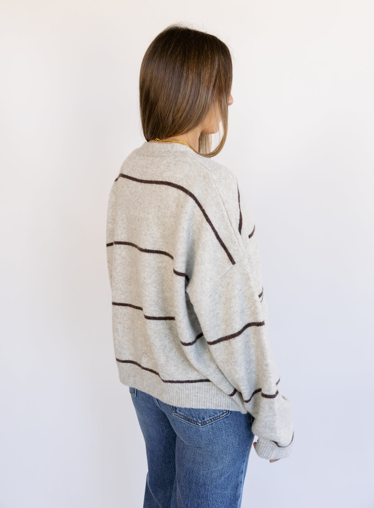 Woman wearing the Juno Striped Knit Cardigan, a mushroom knit cardigan with chocolate stripes and a V-neck