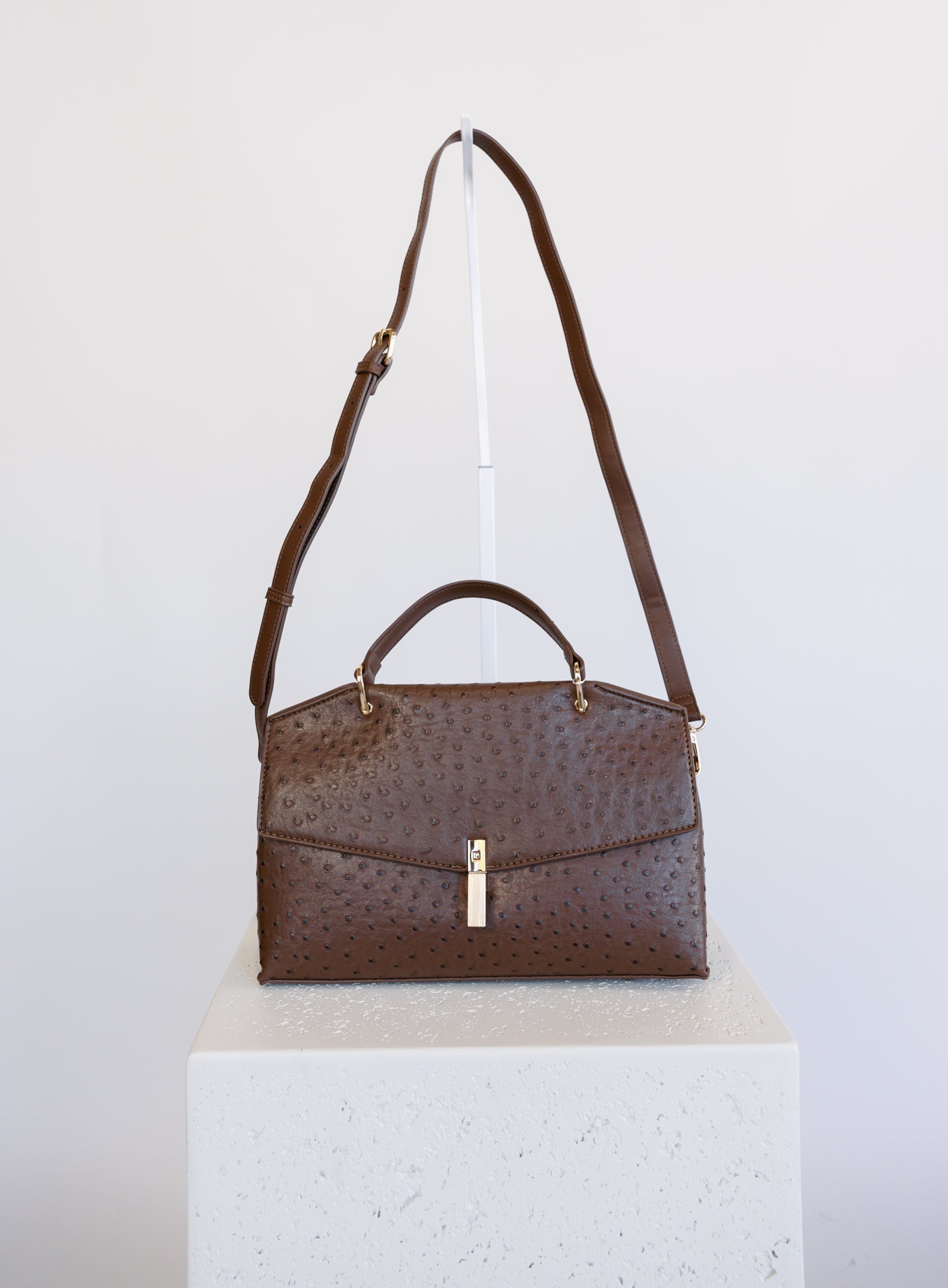 Beatrice Satchel, a brown ostrich-embossed top-handle bag with a gold bar clasp