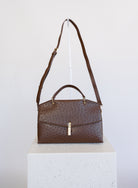 Beatrice Satchel, a brown ostrich-embossed top-handle bag with a gold bar clasp