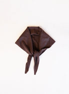Woman wearing the Wrenley Warm Shawl Scarf in Brown, a chocolate brown knit triangle shawl